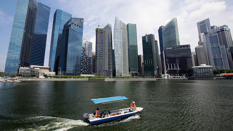 A boat manoeuvres in front of skyscrapers of the Marina Bay Financial Centre in Singapore July 12, 2012.